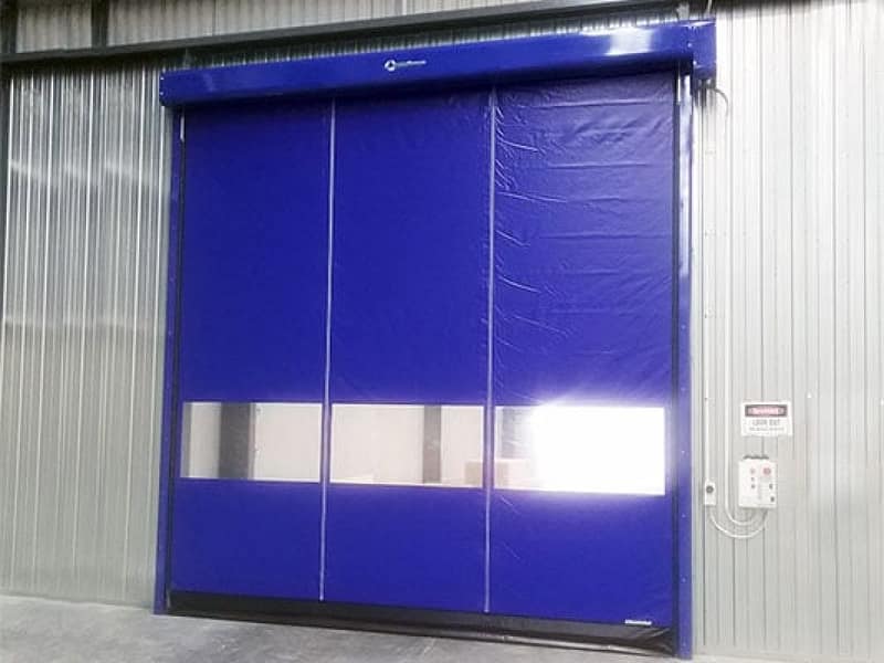Blue high-speed industrial door with clear vision panels installed in a warehouse.